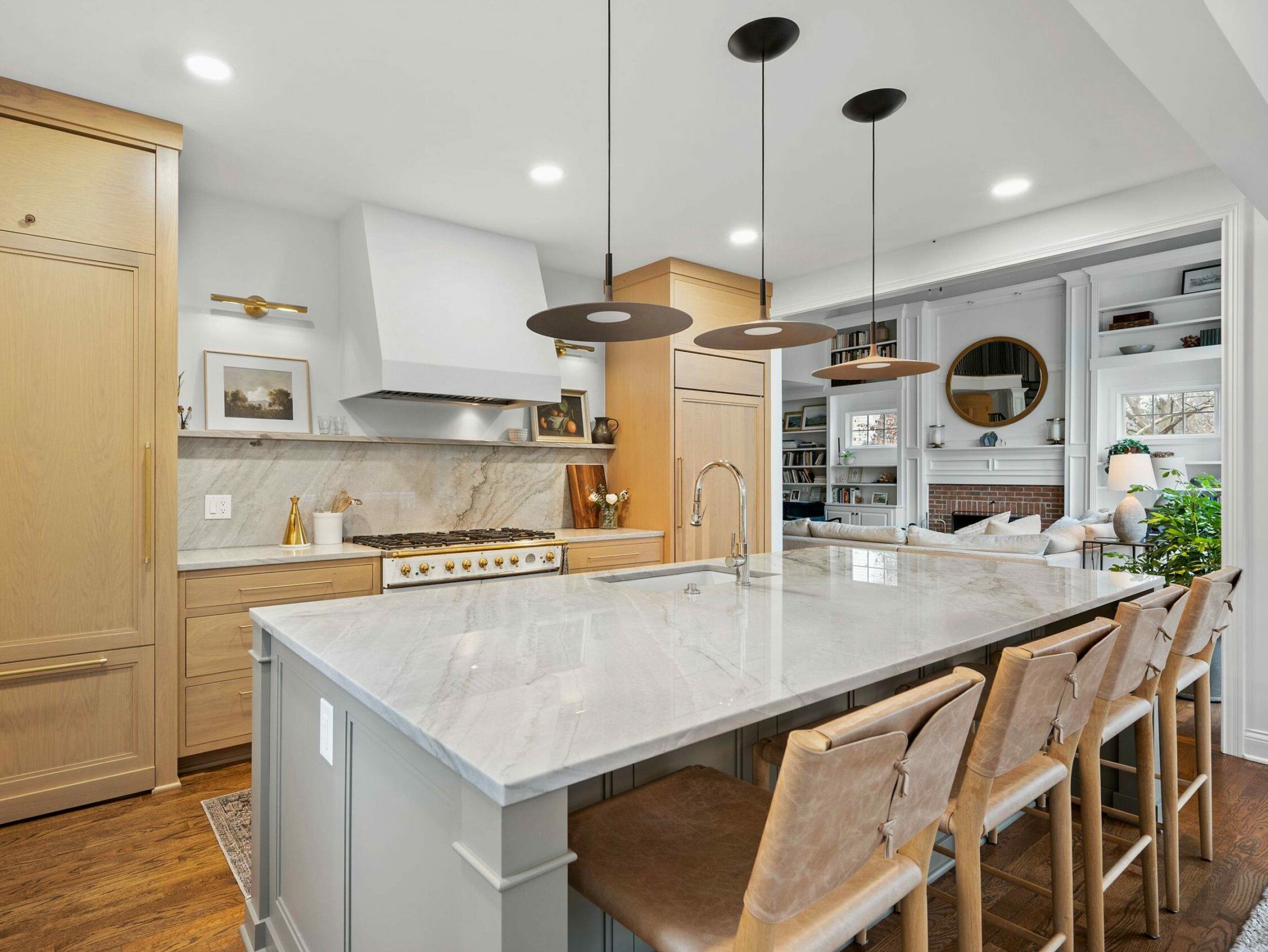 A bright and spacious kitchen featuring light wood cabinetry and a marble island