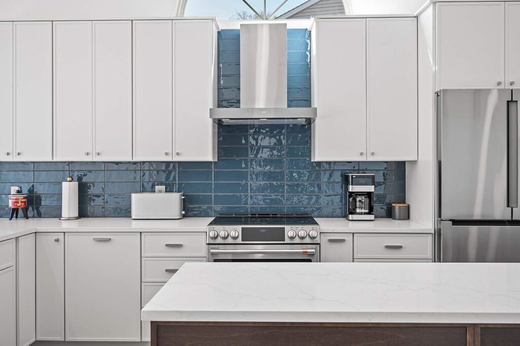 A luxurious, modern kitchen post-renovation. Features a blue tile backsplash