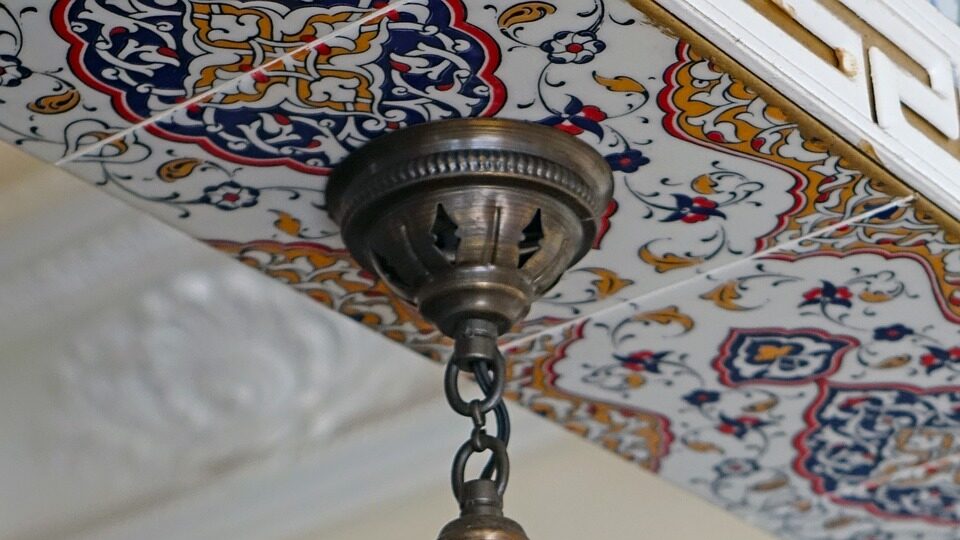 A Moroccan-style tile being used in a kitchen ceiling. Tile is blue, red, and gold.