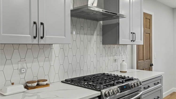 A white kitchen backsplash made with hexagonal tiles