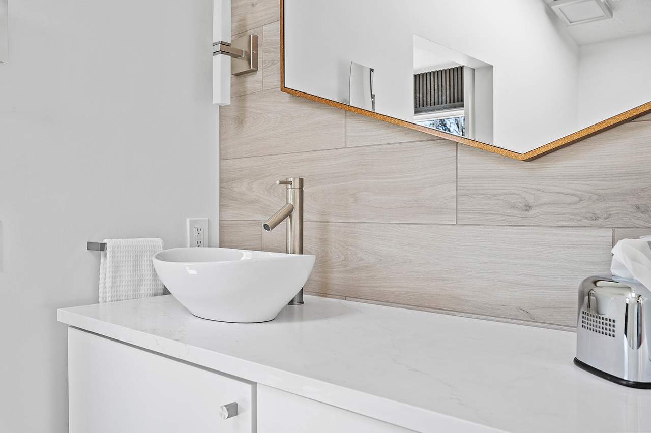 Aurora OH Bathroom Remodel in Greater Cleveland Area. White walls, modern mirror shaped sink and mirror. Modern interior design.